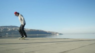 Ağır çekim yakın: kaykay ve ollie atlama genç profesyonel kaykaycı flip hüner sahil mesire üzerinde güneşli yaz aylarında. Kickflip hile Okyanusu yakınlarındaki kaykay ile atlama kaykaycı
