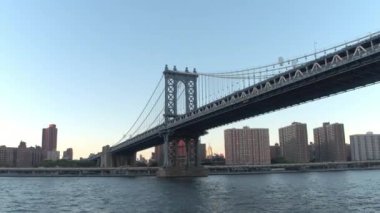 Doğu Nehri Manhattan Köprüsü altında altın gün batımında Hyperlapse düşük açılı görünümü gezi cruise lüks waterfront condominium daire Aşağı Manhattan, New York şehrinin yerleşim bölgesinde boyunca