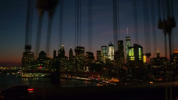 マンハッタン橋をクローズ アップ運転高速道路や現代ガラスの高層ビルに象徴的なブルックリン橋インターチェンジを見下ろす Nyc の街の明かりとダウンタウン夜ライトアップ — ストック動画