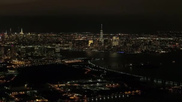 ヘリは夜間飛行工業地帯のニュージャージー港の上と象徴的な Nyc ダウンタウンのスカイラインを見渡す明るい高層ビルとブルックリンやクイーンズ街並みバック グラウンドで — ストック動画