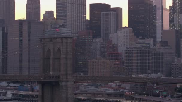 在美丽的粉红色黎明驾驶曼哈顿大桥俯瞰标志性的布鲁克林大桥 曼哈顿商业区的现代玻璃摩天大楼 在金色清晨的色调中闪耀璀璨 — 图库视频影像