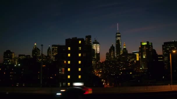 クローズ アップ 高速道路走行マンハッタン橋を渡ってニューヨーク市のダウンタウンのビジネス地区へ過去のバック グラウンドで有名なガラスの摩天楼と高級住宅タワー ブロック夜 — ストック動画