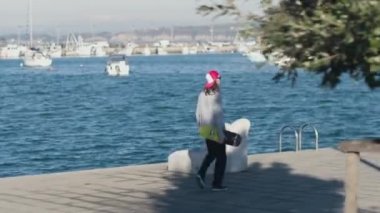 Yakın: Mutlu kaykaycı kaykay, paten ve yayalar geçmiş beton okyanus kıyısında güneşli günde deniz kenarında atlama başlar atlar. Atlama ve liman önünde sürme patenci