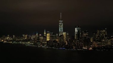 Hava Heli Shot: Skyline görünümü New York Yarımadası ikonik Downtown Manhattan mali ile bölgesinin ünlü büyük waterfront gökdelenler ve dev ofis binaları geceleri parlayan ışıkları ile alev aldı.