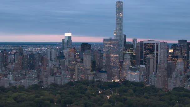 空中のヘリ ショット ライトの巨大なガラスの高層ビル オフィスビルや高級 Condomoniums 静かな早朝の緑豊かな中央公園を見下ろす窓に輝くニューヨーク市マンハッタン — ストック動画
