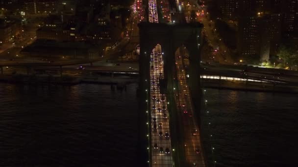 空中直升机射击 没有明显的商标汽车交通移动横跨标志性的布鲁克林大桥照亮了在梦幻般的夏日夜晚在纽约市的灯光 上下班高峰期上班的人 — 图库视频影像