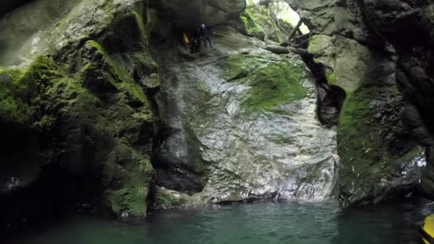 Fpv クローズアップ スロベニアの美しい峡谷で楽しいキャニオニング体験に幸せなアクティブな冒険的な若い男 さわやかな川のプールに水滴を飛び散らす高い急な岩の壁を飛び降りる — ストック動画