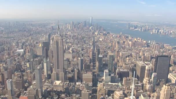 空中特写 飞行在阳光明媚的中城曼哈顿的第六大道上空 穿过帝国大厦和纽约市的公寓大楼 向市中心的摩天大楼飞去 — 图库视频影像