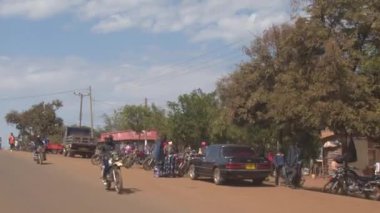 Karatu, Tanzanya - 10 Haziran 2016: Çekici güzel canlı kentsel yaşam renkli tozlu sokaklar sıcak Afrika City. Yerel halkın komşuları'nda küçük dükkanlar tam seyahat scooter sürüş