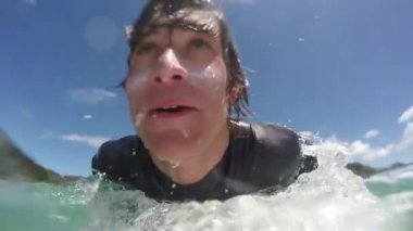 Ağır çekim yakın çekim: dalgaların altında dalış ve doğru sanatçısını dışarı kürek çekmeye mutlu genç sörfçü ördek. Yeni Zelanda okyanusta sörf neşeli surfer dude