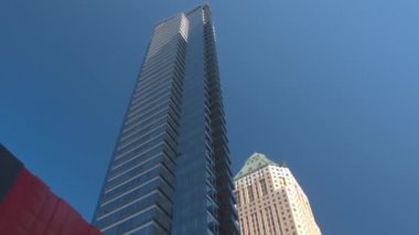 Büyük şehirde hışırdayan yeşil ağaç yapraklarının arkasındaki çağdaş camsı gökdelenler. Kentsel apartmanlar.