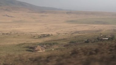 Yakın: Safari oyunu çamur, geleneksel dairesel evler ile büyüleyici küçük Massai göçebe yerli kabilesi köy sürüş sopa ve arka planda güzel büyümüş Dağları ile çim