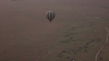 Anteni: sıcak hava balon safari sonsuz ova ovaları, dolambaçlı nehir ve turistler sürüş tozlu kalabalık yollar oyunu yüksekten uçuyor. Bozulmamış Afrika vahşi izlerken hava seyahat