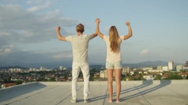Ağır çekim yakın Dof Up: kız ve elele ve onları yükselen güneş tarafından aydınlatılmış kentsel şehir üzerinde çatı üzerinde havada yükselterek mutlu çocuk heyecanlı. Mutlu insanlar başarı, kutlama hayatı
