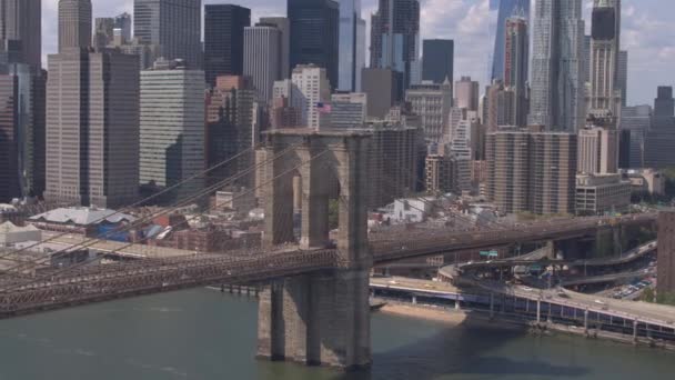美丽的城市景观的标志性纽约市的摩天大楼 办公楼和金融区的高加注塔 繁忙的布鲁克林大桥高速公路与汽车和半卡车在晴朗的一天 — 图库视频影像