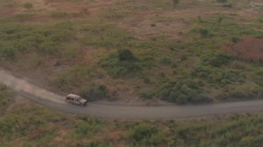 Hava: safari jeep geniş kurak Afrika otlak savannah alanlarından sürüş arkasında, toz bulutu bırakarak oyun sürücü üzerinde uçan. Güneşli akşam vahşi doğada çarpıcı üzerinde muhteşem bir manzara