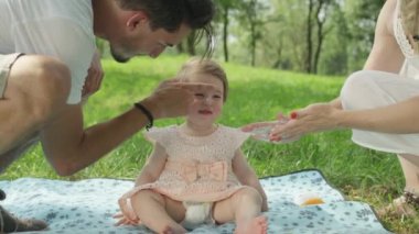 Ağır çekim, Close Up, Dof: suncream bebek kız yumuşak yanaklarda koyarak mutlu ve bakım anne-babalar, bacaklar ve güneşlenmek duyarlı genç cildi korumak için vücut almak o sağlıklı ve nemli