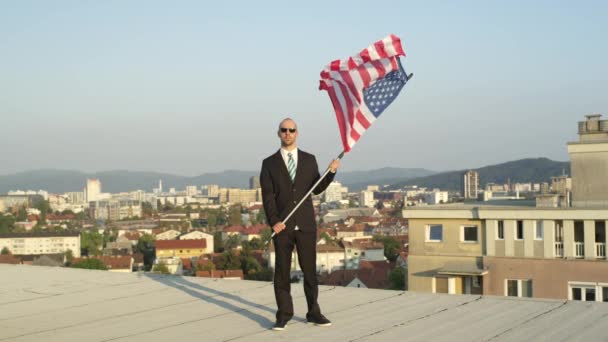 スローモーションをクローズ アップ 満足して成功した実業家と誇らしげにアメリカの国旗を保持している 成功を祝う 自由を支える背の高い建物の上に立っている愛国者 — ストック動画
