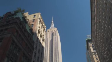 Ağır çekim yakın çekim: sokakta ikonik tarihi gökdelen Empire State Binası Midtown Manhattan'ın finans merkezi New York'ta bulunan dan mesafe daireler, bloklar arasında sürüş