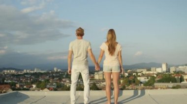 Ağır çekim yakın Dof Up: kız ve elele ve onları yükselen güneş tarafından aydınlatılmış kentsel şehir üzerinde çatı üzerinde havada yükselterek mutlu çocuk heyecanlı. Mutlu insanlar başarı, kutlama hayatı