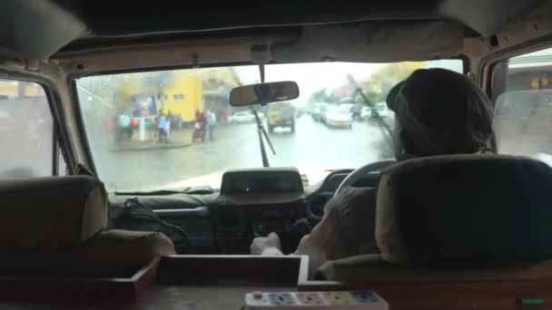 アルーシャ タンザニア 2016 地元のタクシー ドライバー ツアーは美しいですが 雨の夏の日に多様なカラフルな詰まったアフリカ都市からの観光客を導きます 濡れた車の窓を通して観光出張 — ストック動画