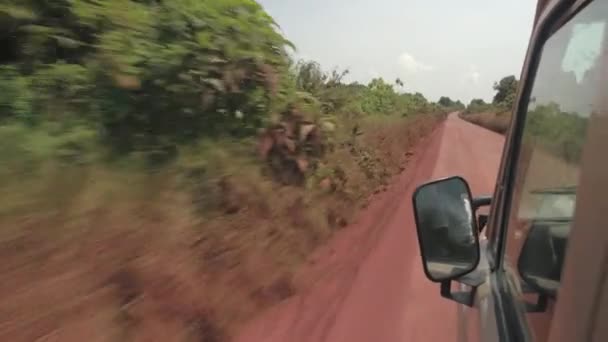 クローズ アップ すべて地形サファリ ジープ息をのむの密なアフリカ サバンナ ウッドランドのゲーム ドライブで観光客を運転をほこりの多い道路での高速化します 赤色土ほこりに覆われた道路に沿って美しい植物 — ストック動画