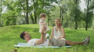 Ağır çekim, Close Up, Dof: Pastoral kaygısız ailesiyle Jack Russell evcil köpek kaliteli vakit yerel parkta güneşli yaz gününde. Baba, midesi üzerinde duran ile oynarken neşeli tatlı bebek kız