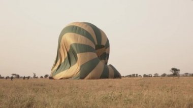 Yakın: sonsuz Serengeti ovaları rüya gibi vahşi Afrika üzerinden sıcak hava balon Safari'de unutulmaz uçuş sonra disembarking turistler. Varış ve kısa çim savana sahası güneşli akşamı açılış