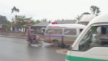Arusha, Tanzanya - 10 Haziran 2016: zavallı canlı ticari ve konut kırsal Afrika çamurlu Köyü ile mutlu turist kötü hava yağmurlu gün sürüş eski paslı renkli turistik otobüs tur