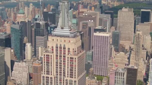 空中をクローズ アップ レンズのズーム 象徴的なエンパイアステートビル サニー ミッドタウンにニューヨーク市のセントラルパーク ハドソン川マンハッタン バック グラウンドで周りに飛んで ニューヨーク上空にヘリコプター — ストック動画