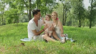 Ağır çekim, Close Up, Dof: Central Park'ta kaliteli zaman zevk ve kameraya sallayarak pastoral gülümseyen beyaz aile. Çocuk ile oynarken oldukça gülümseyen anne ve Genç babası olmakla gurur duyuyorum