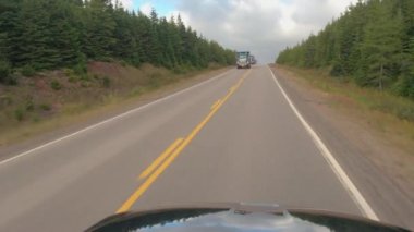 POV, Close Up: doğada Kanada backcountry yolu boyunca sürüş kargo nakliye yarı kamyon. SUV araç yönlendirme kırsal alanda yoğun Ladin orman yolu boyunca sürüş yolculuğa