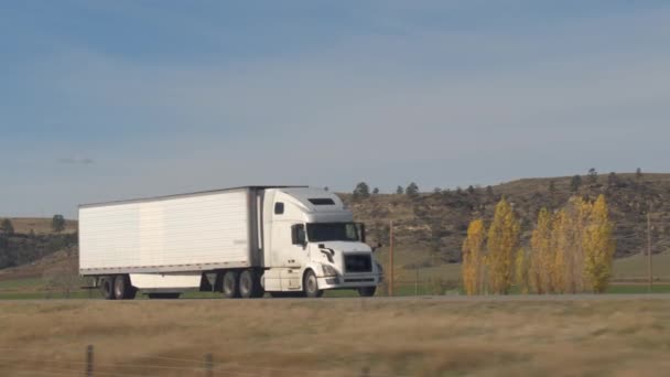 集装箱半卡车运输货物行驶在州际公路沿线陡峭的岩石山坡上的农村 货船运输货物沿公路行驶 — 图库视频影像