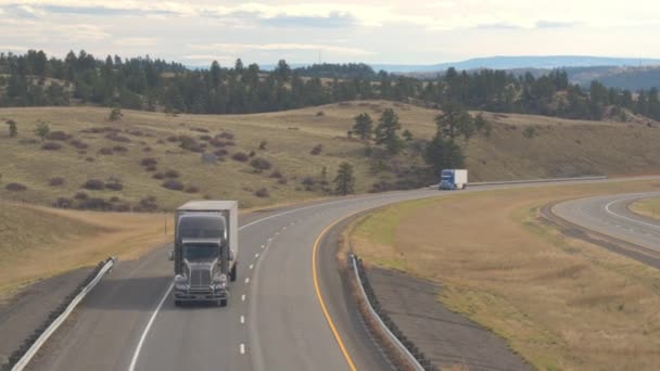 空中閉じるを上を飛んで大平原にアメリカの荒野を走る高速道路 車の輸送貨物セミトラック人ロッキー山脈に向かって移動 — ストック動画