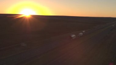 Hava: çöl yoluyla meşgul karayolu üzerinde gece karanlığında Great Plains, ABD sürüş mal yüklü yük araçlar yukarıda uçan. Taşınması ve altın ışık günbatımında kargo nakliye yarı kamyon