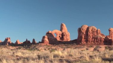 Kırmızı kaya oluşumları mavi gökyüzü Arches National Park Utah ABD karşı güneşli sabahı çarpıcı. Uzaydan kumtaşı sütunlar, windows ve kemerler manzara oluşumu sıcak çölde gün batımında.