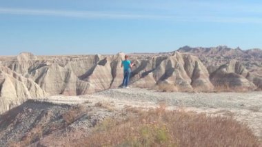Neşeli genç kadın gezgin doğal Badlands Ulusal Parkı güneşli günde Güney Dakota'da, ABD çekim. Kumtaşı dağ çöl vahşi keşfetmek ve fotoğraf makinesi ile çekim mutlu kız