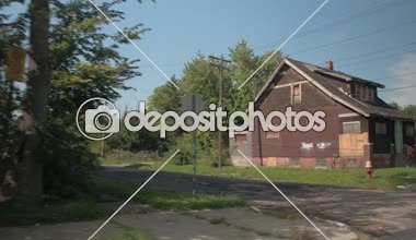 Yakın: Detroit, ABD zavallı Mahallesi'nde terk edilmiş yıkık ev geçmiş kötü kırık cadde boyunca sürüş. Güneşli varoşlarda boş terk edilmiş evde. Şehir çürüyen içinde kırık ve yıpranmış asfalt delikler