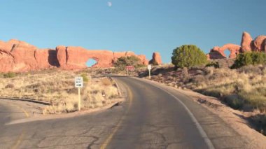 İlk kişi görünümü: boş bir yolda bir çarpıcı Arches National Park Utah üzerinden güneşli günde sürüş. Virajlı yol United belirtilen şaşırtıcı kırmızı kaya kumtaşı oluşumları sıcak çöl geçmiş sarma