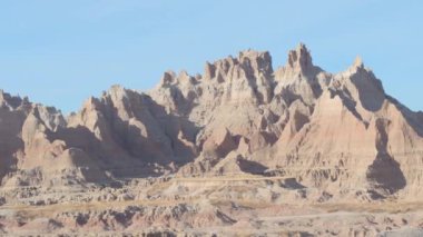 Yakın: Dik sivri kumtaşı mountaintops açık mavi gökyüzü Güney Dakota'daki Badlands ulusal parkta karşı. Great Plains otlaklar erozyona uğramış kayalık dağ oluşumları ile uzay manzara