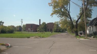 Kırık boyunca sürüş yol güzel konut evler Detroit, Amerika Birleşik Devletleri çürüyen içinde tuğla inşa kapalı terk edilmiş fabrikası doğru geçmiş zarar görmüş. Sanayi Bölgesi ıssız değil çalışma bitki