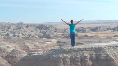 Zevk ve rahatlatıcı güneşli gökyüzü doğru kaldırdı kollarını ile kumtaşı dağın Badlands Ulusal Parkı'nda tepesinde duran Slow Motion mutlu kadın uzun yürüyüşe çıkan kimse. Gezgin keşfetmek Badlands vahşi