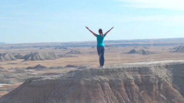 Zevk ve rahatlatıcı güneşli gökyüzü doğru kaldırdı kollarını ile kumtaşı dağın Badlands Ulusal Parkı'nda tepesinde duran Slow Motion mutlu kadın uzun yürüyüşe çıkan kimse. Gezgin keşfetmek Badlands vahşi