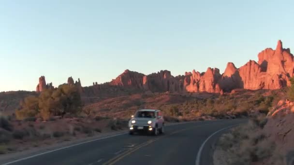 時間の経過 は晴れた朝に空はユタ州の見事なアーチーズ国立公園を通して道運転 夕暮れ時暑い砂漠ですばらしい赤い岩の砂岩過去巻曲線道路 — ストック動画