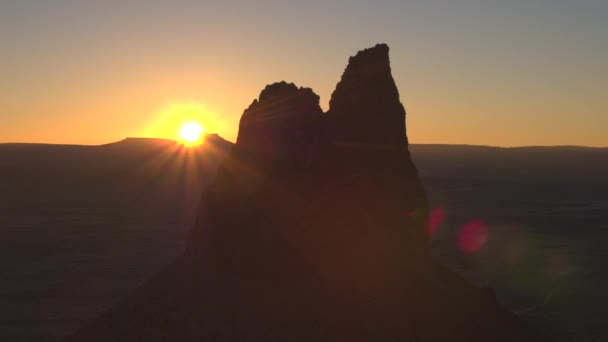 空中クローズ アップ オレンジ色の夕焼け空に対して奇妙な火山の山頂の周りに飛んでいます 夜明けに火山岩の砂漠で地球外の宇宙の風景です ロッキー山脈を通して輝く太陽 — ストック動画