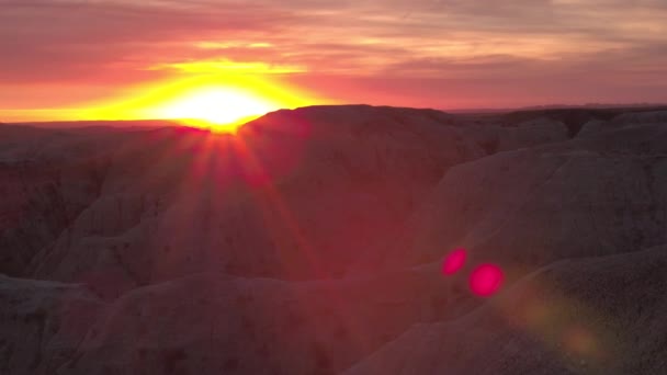 美しい赤みの後ろに沈む無限砂岩山地バッドランズ国立公園の夕暮れ時 ダコタ州アメリカ合衆国の浸食された岩山形成上見事な日の出 — ストック動画