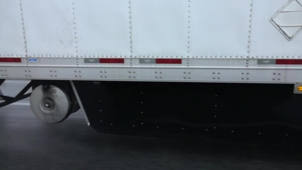 シャーシ雨嵐の間に悪い気象条件でウェットの高速道路に沿って運転半トラックのタイヤからスプレー雨滴のスローモーションをクローズ アップ 雨の中で大型トラック運搬貨物 — ストック動画