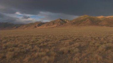 Hava: Geniş açık çimenli alanlar Great Plains ve güzel çöl vadi görkemli buruşuk dağ yamacı altında altın ışık. Dramatik siyah bulutların üzerinde yağmur fırtınası önce Rocky Dağları