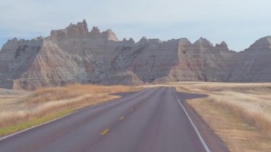 FPV: rocky kumtaşı oluşumları ile pitoresk Badlands peyzaj boş yol boyunca sürüş. Güney Dakota'daki Badlands Çölü seyahat. Yolculuk boyunca Amerika Birleşik Devletleri.