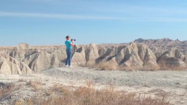 Neşeli genç kadın gezgin doğal Badlands Ulusal Parkı güneşli günde Güney Dakota'da, ABD çekim. Kumtaşı dağ çöl vahşi keşfetmek ve fotoğraf makinesi ile çekim mutlu kız